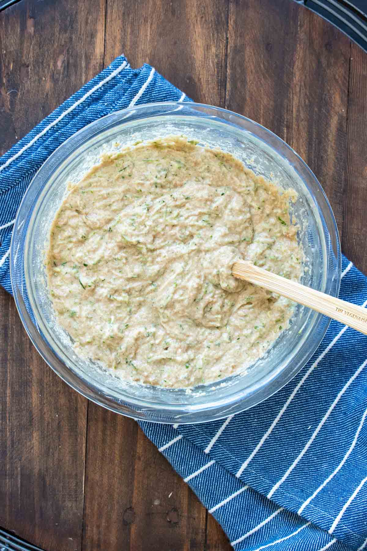 A batter in a glass bowl with a spatula mixing it