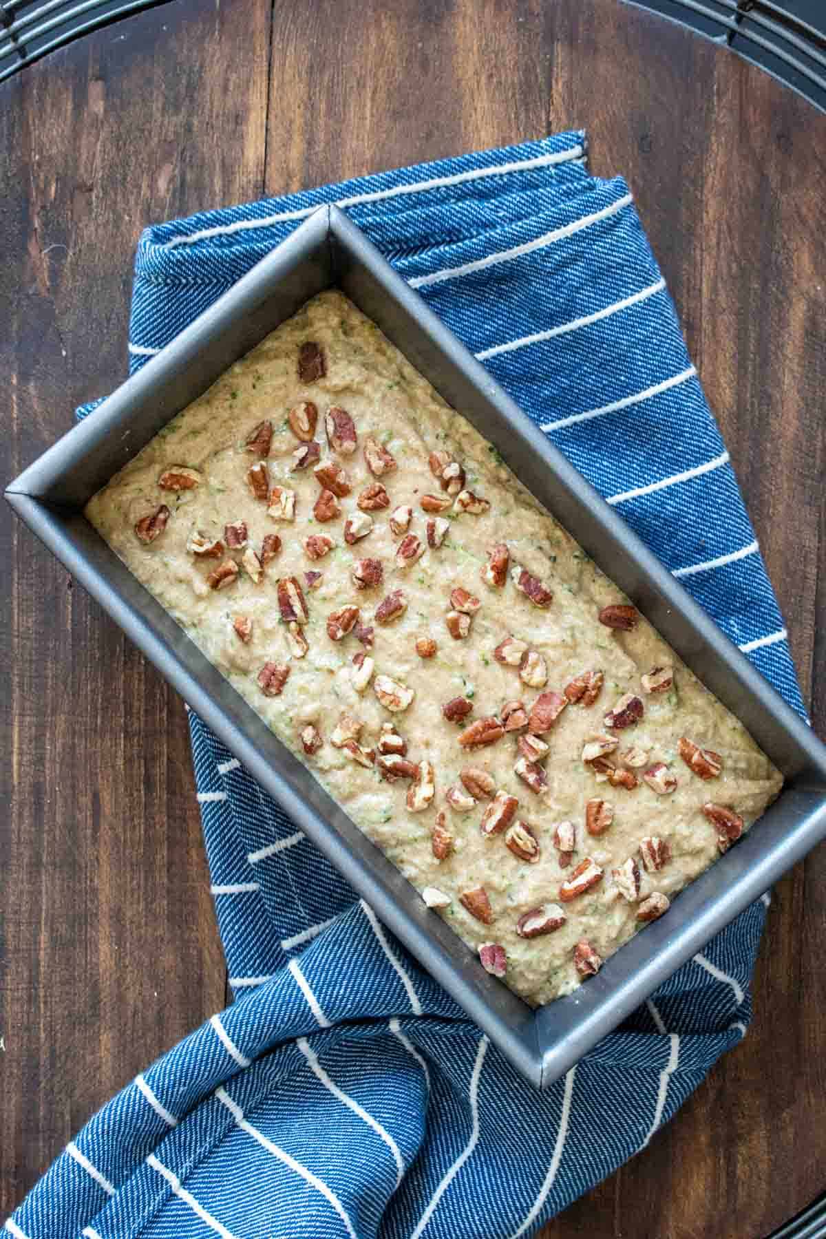 Top view of a bread pan with batter inside topped with nuts