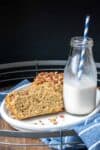 Slices of bread topped with nuts on a white plate with a jar of milk