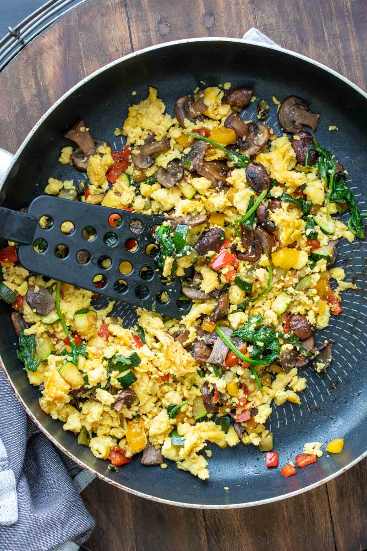 Spatula mixing scrambled eggs with veggies in a pan