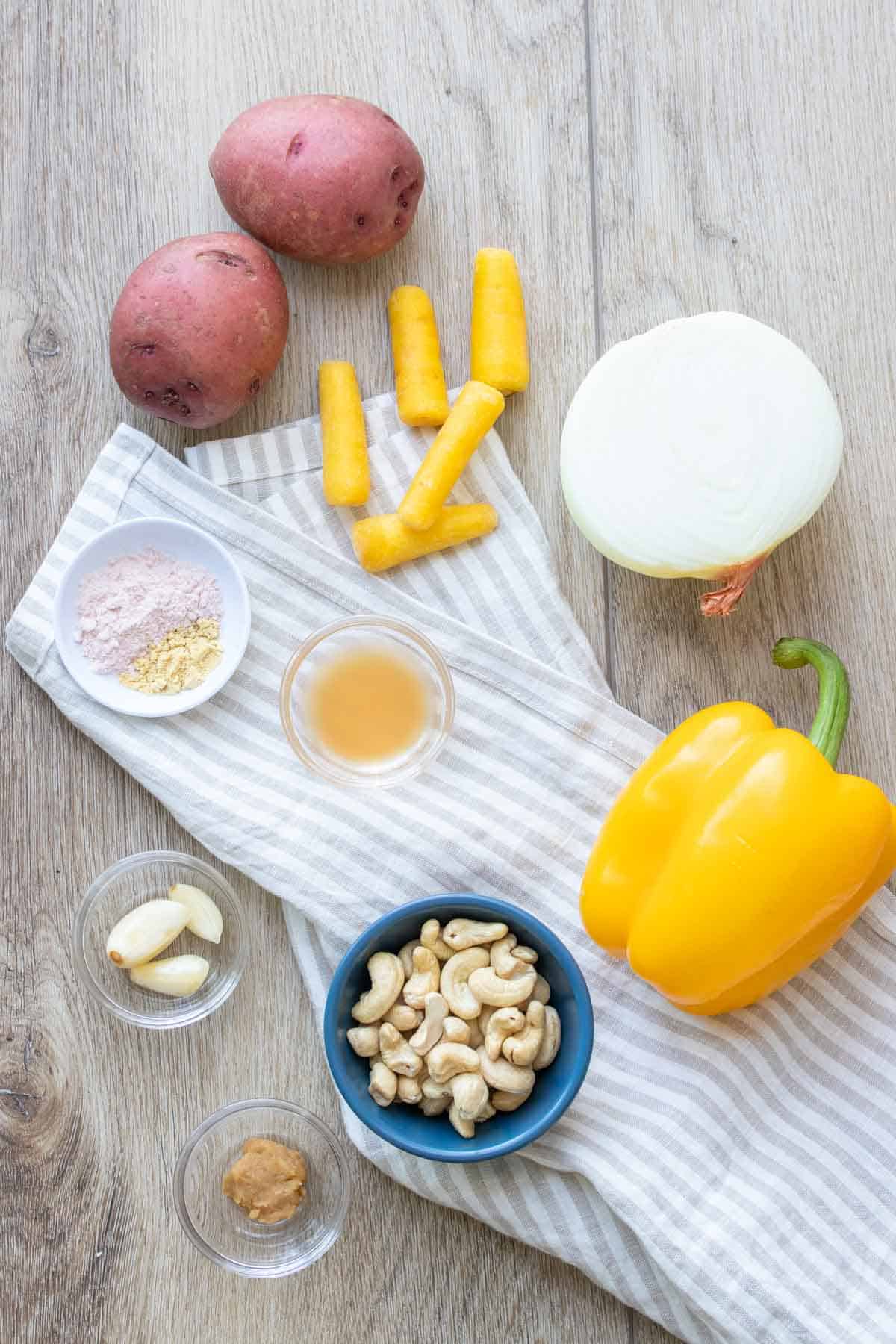 Veggies, cashews, garlic, vinegar and spices laid out on a wooden surface