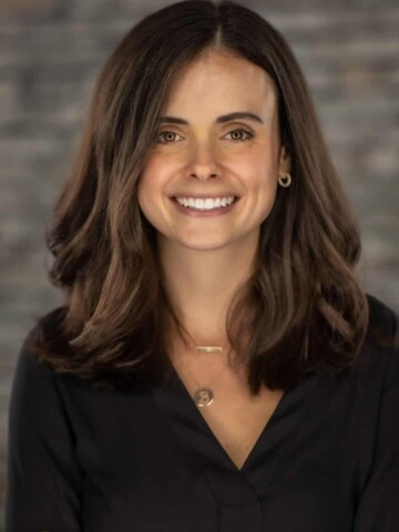 Woman with brown hair and wearing a black shirt smiling at the camera