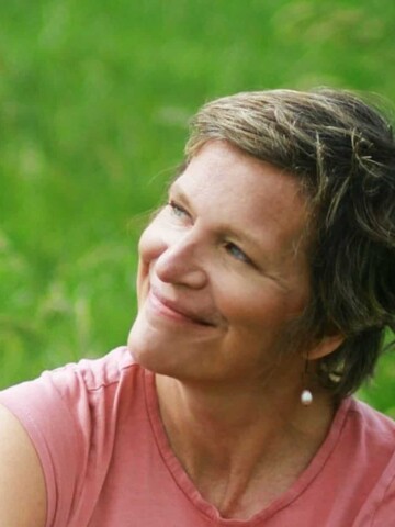 A woman in a pink shirt looking away from the camera and smiling