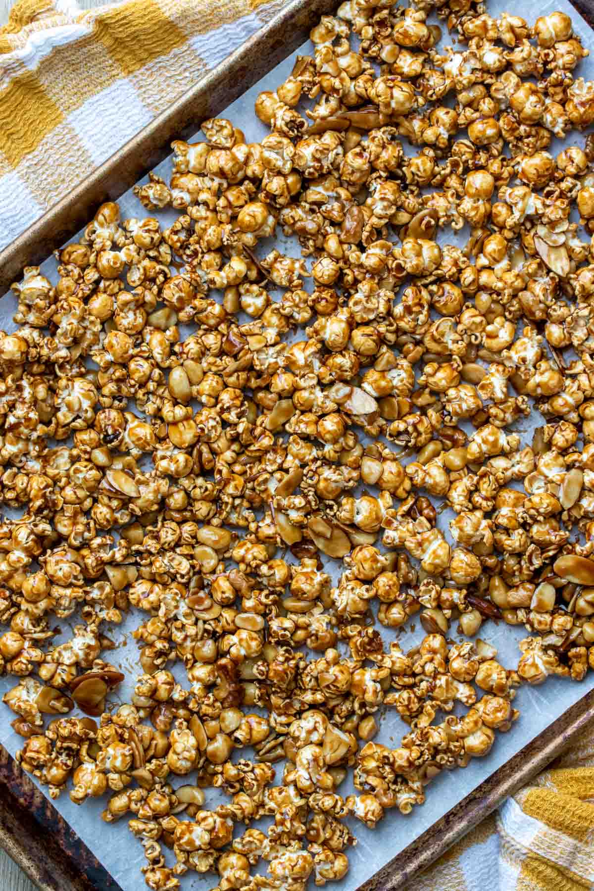 Baking sheet with popcorn covered by caramel spread out over it