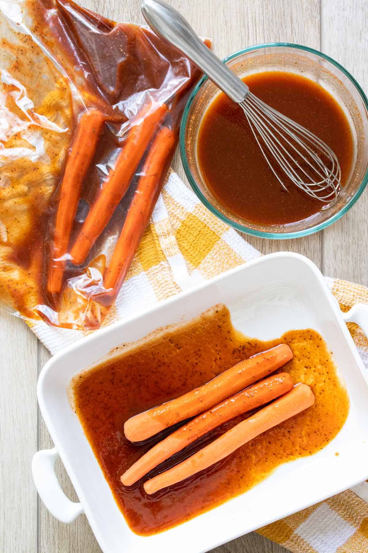 Long carrots in a white pan with marinade next to a bowl with the marinade and the carrots and marinade in a bag