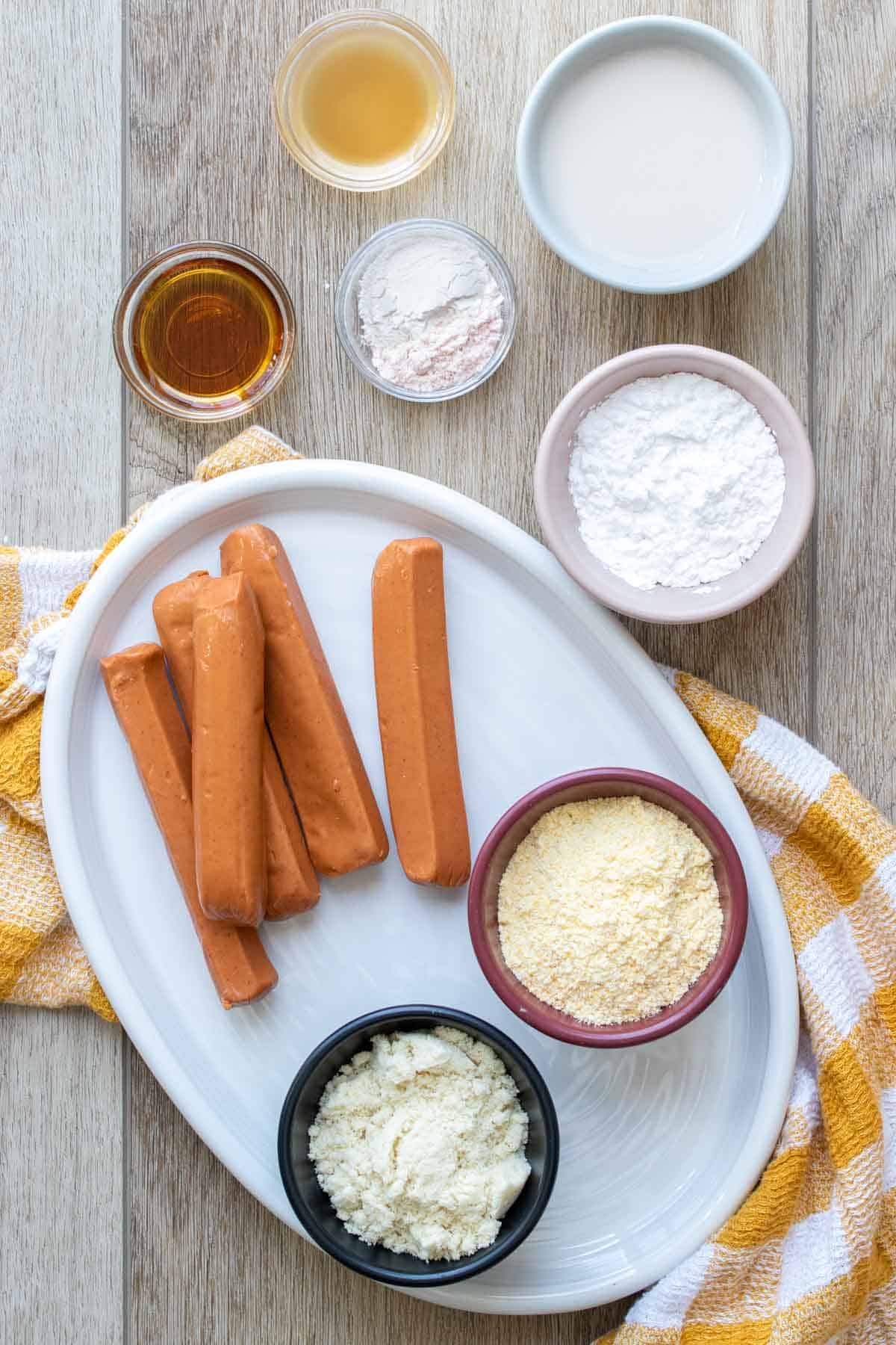 White platter with hot dogs and ingredients to make corn dogs