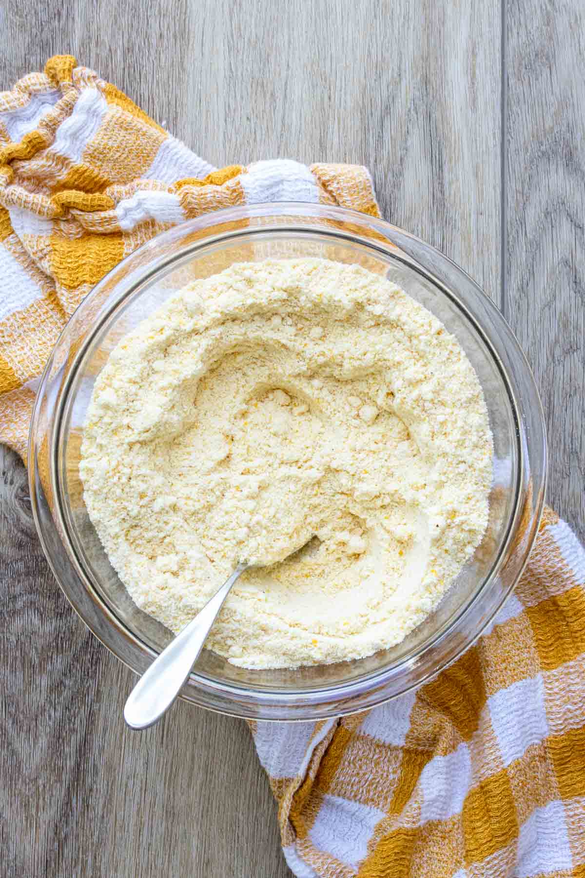 Glass bowl with a cornmeal mixture and a spoon inside