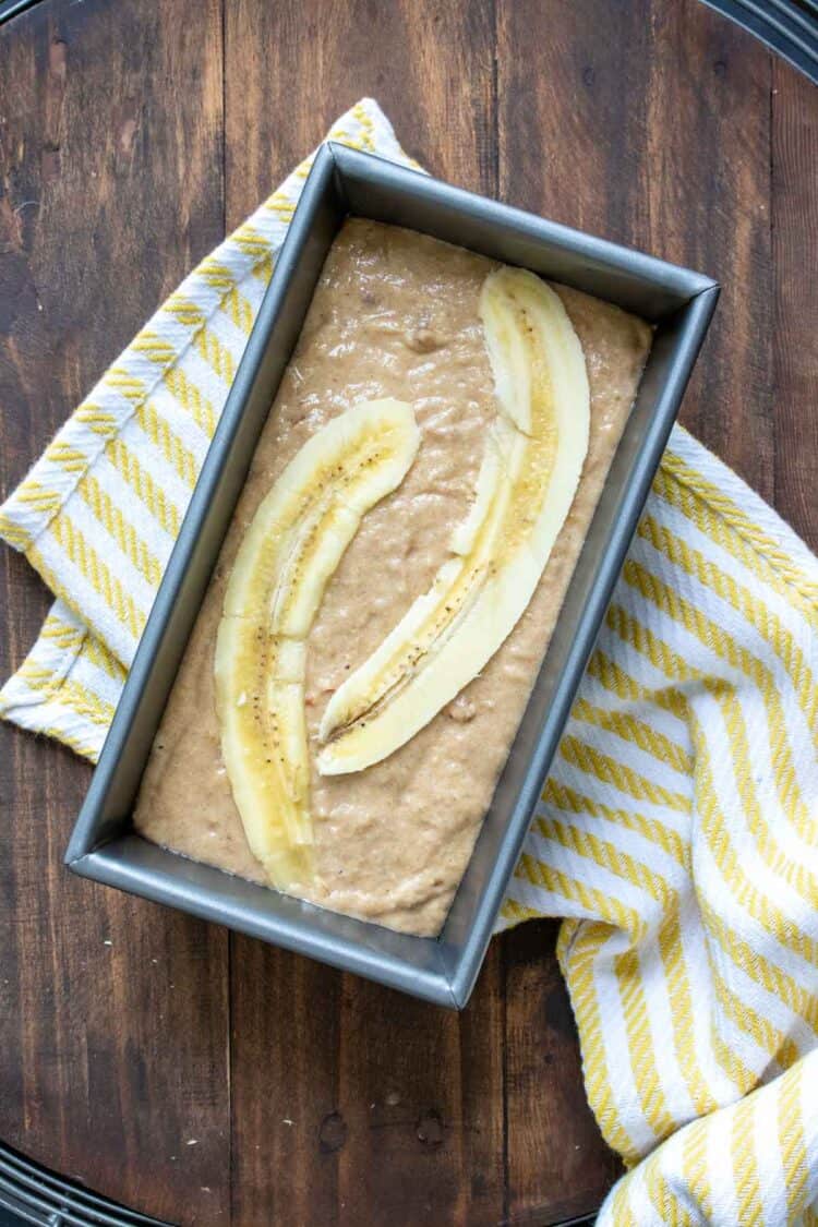 Raw batter topped with sliced bananas in a metal pan