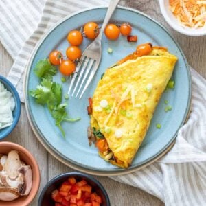 A turquoise plate with a veggie omelet and cherry tomatoes on it.