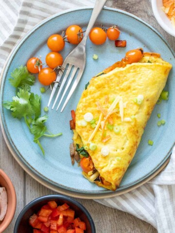 A turquoise plate with a veggie omelet and cherry tomatoes on it.