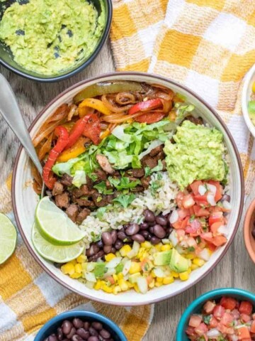 A close up of a bowl with grains, beans and veggies on a yellow checkered towel