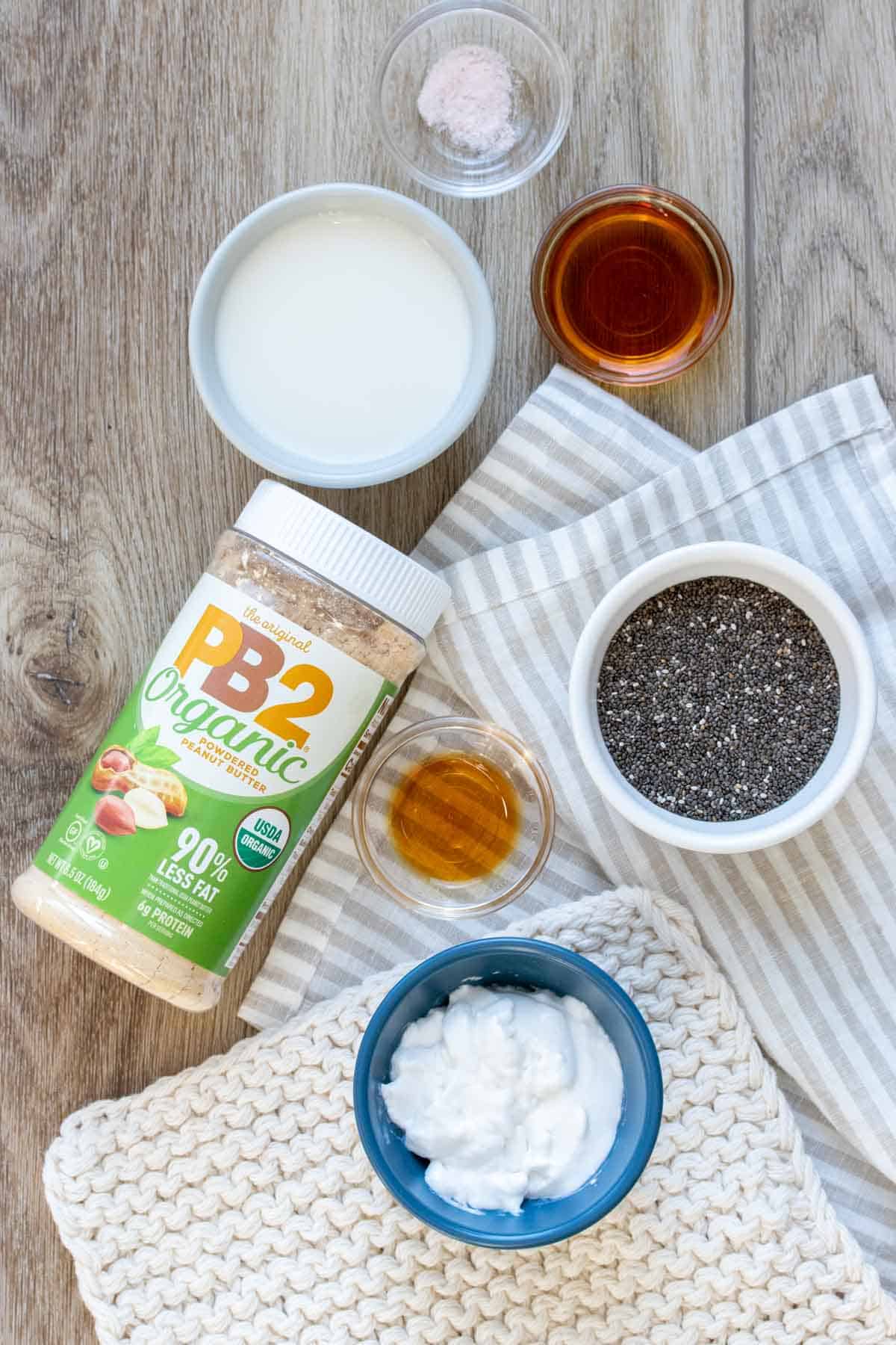 Top view of ingredients needed to make a chia seed pudding using peanut butter powder from a jar with a green label.