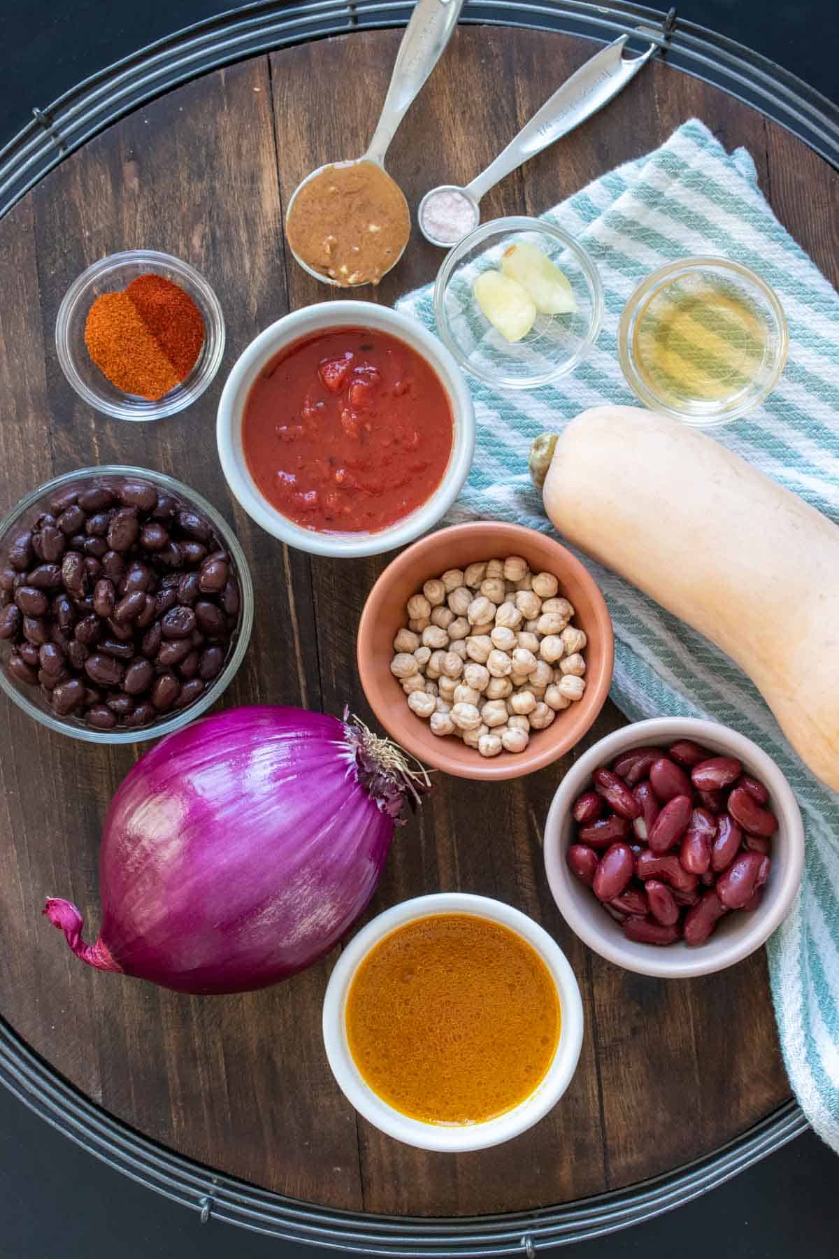 Top view of a wooden tray with ingredients to make a bean chili with squash