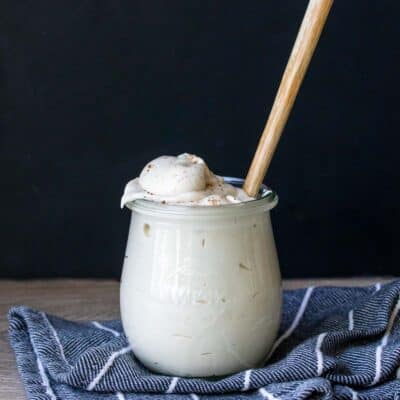 A glass jar filled with a creamy white sauce with a spoon in it