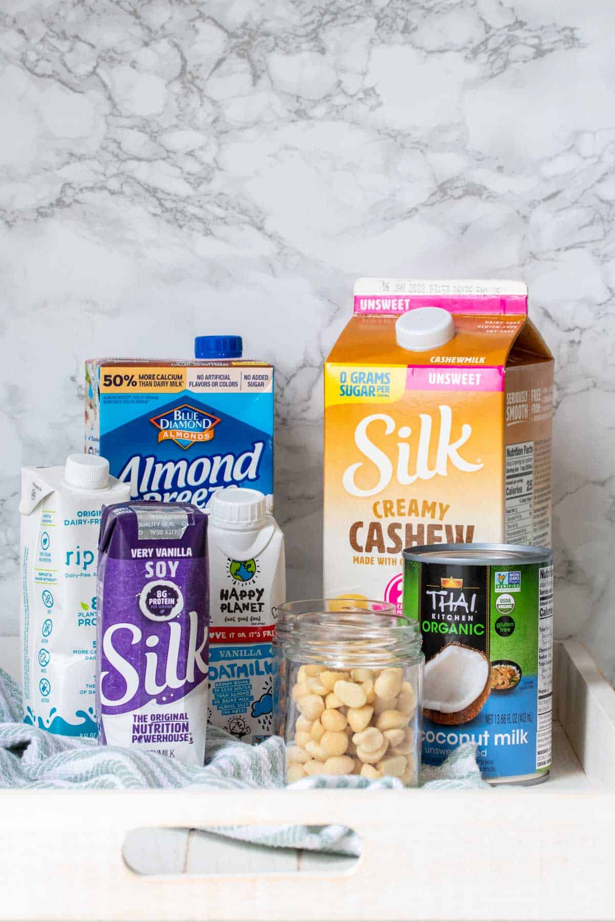 A group of dairy free milk cartons of varying sizes on a white tray