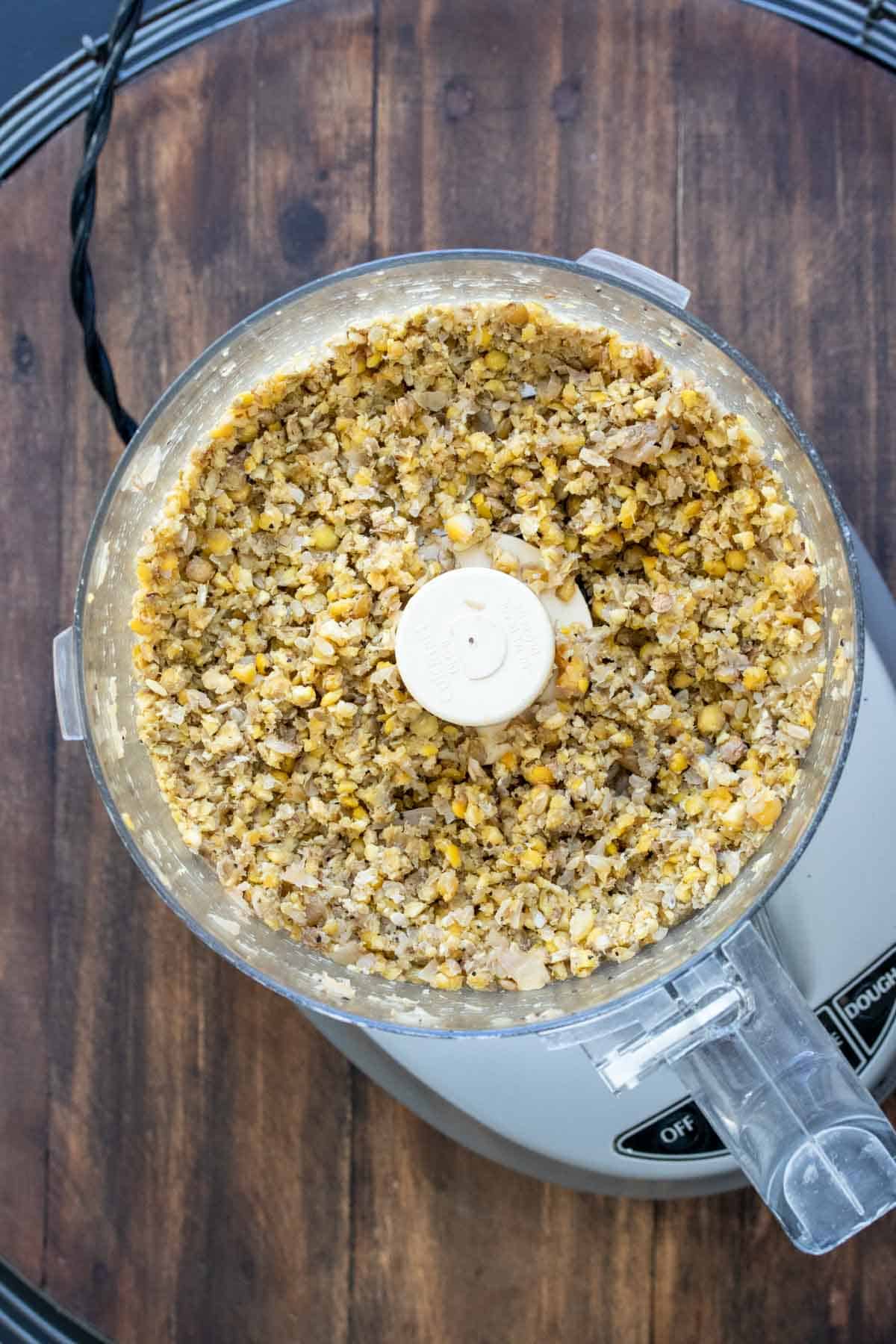 Top view of food processor with a crumbled chickpea and lentil mix