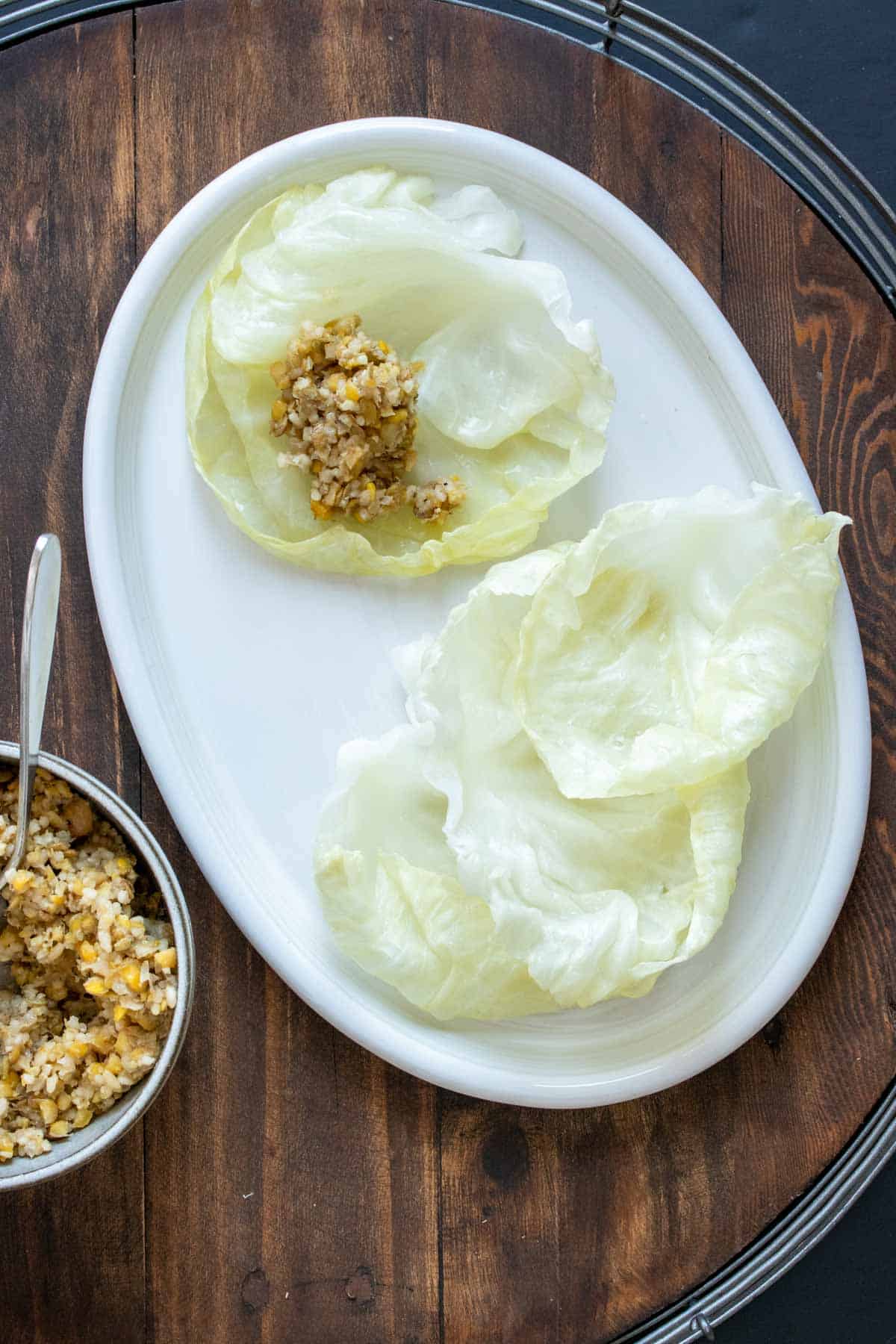 White platter with cabbage leaved on it and one has filling on top