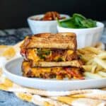 A grey plate on a yellow checkered towel with a stack of veggie grilled cheese on it.