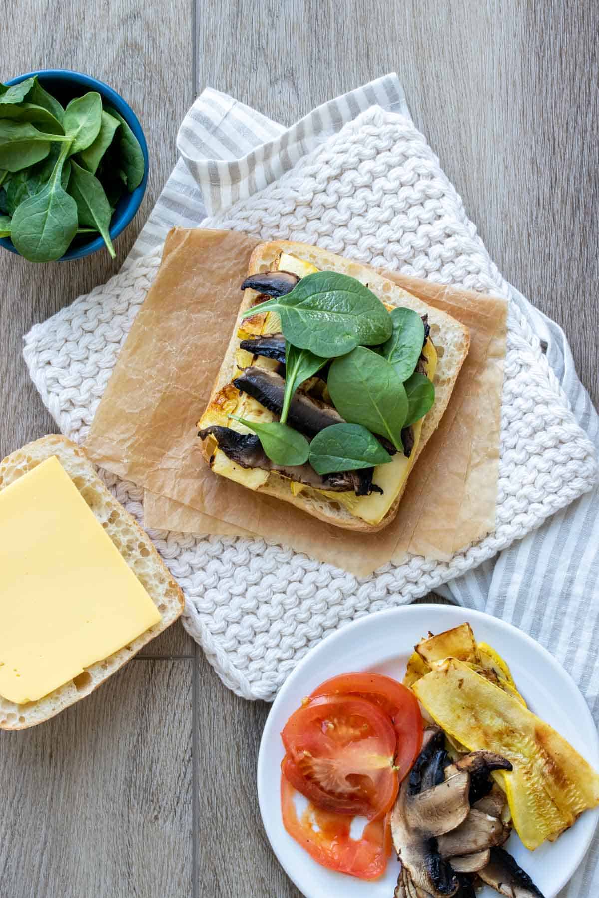 Top view of a sandwich being layered and built next to toppings