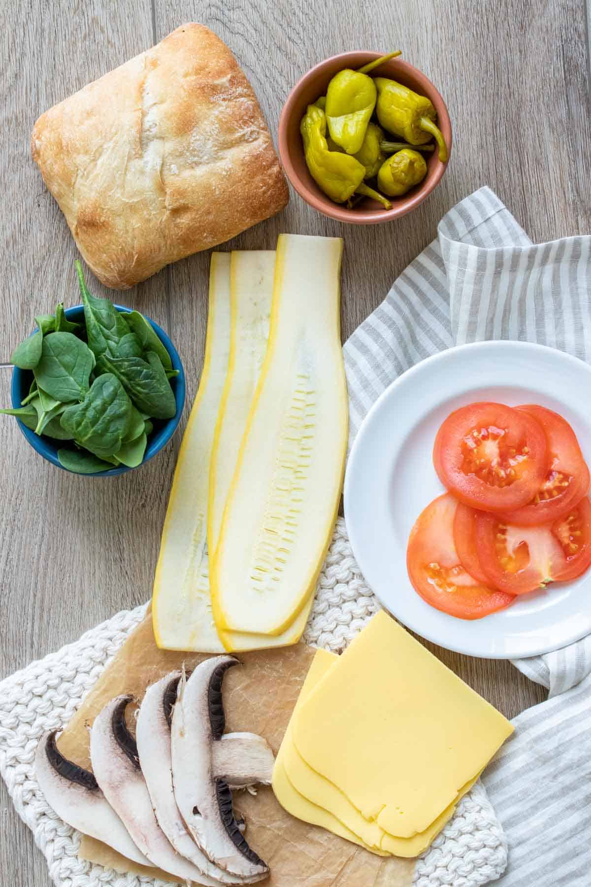 Top view of sliced veggies with bread and cheese on a striped towel