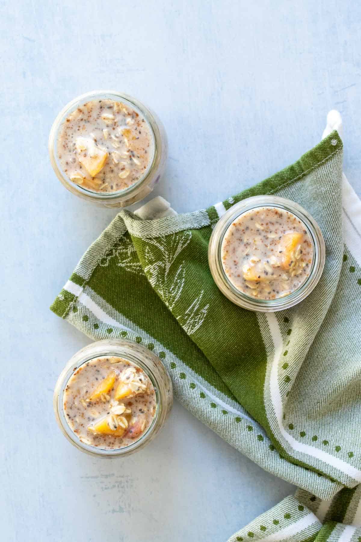 Top view of three glass jars filled with oats, milk and peaches