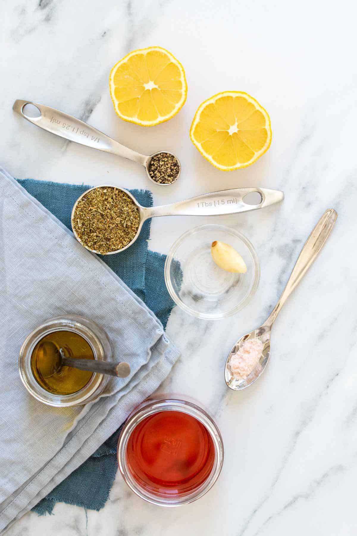 Top view of ingredients on a marble surface needed to make a Greek salad dressing