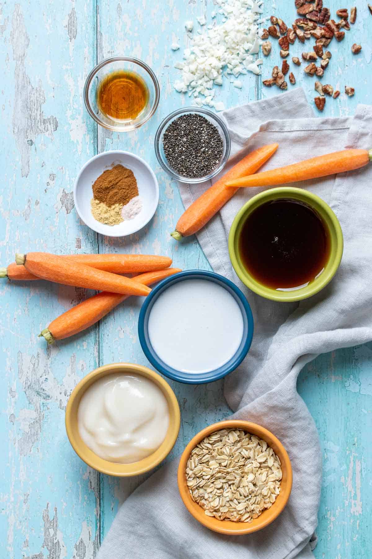 Top view of a blue wooden surface with ingredients needed to make carrot cake flavored overnight oats