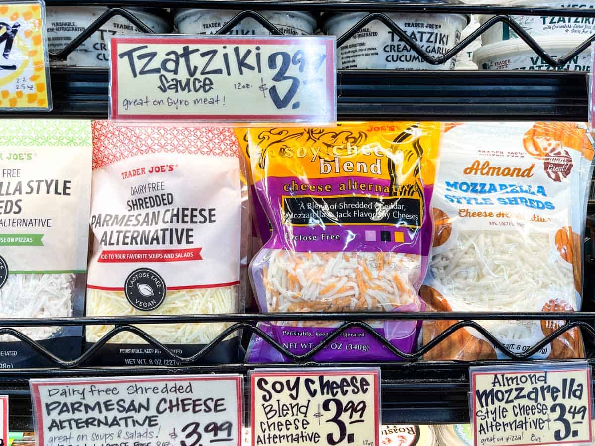 A refrigerated section of a grocery store with a shelf of dairy free shredded cheeses