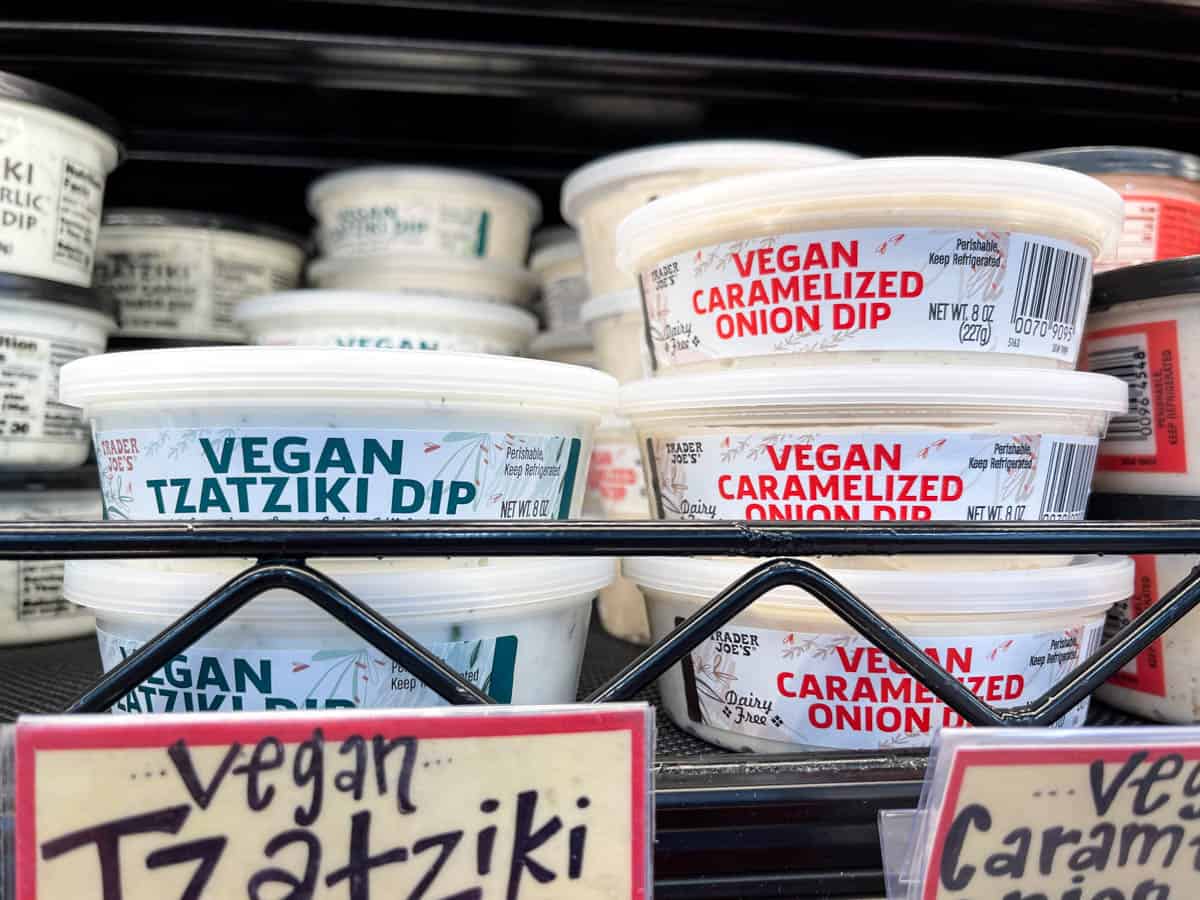 Containers of vegan dips on a shelf in a grocery store