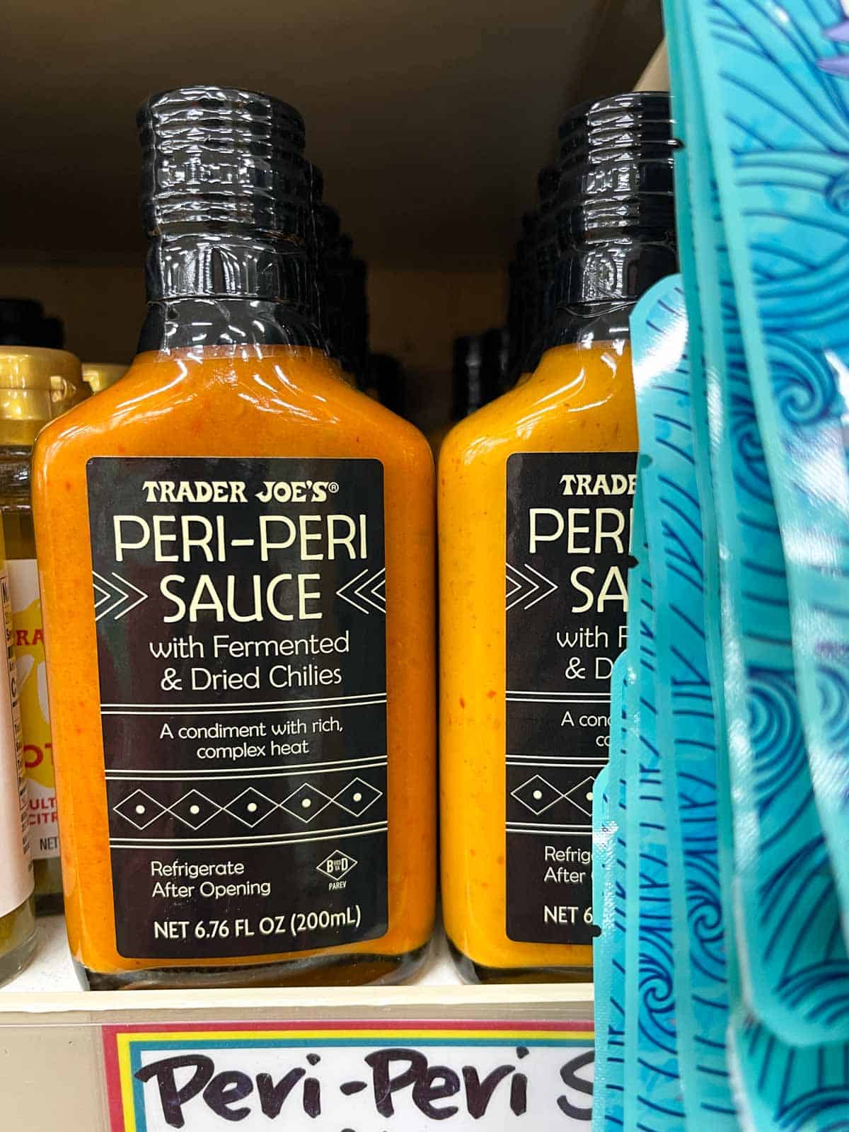 Jars of orange peri-peri sauce on the shelf of a grocery store