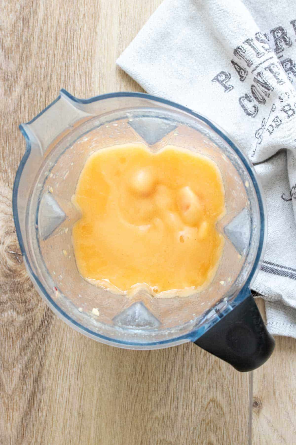 Top view of a peach colored frozen slushie in a blender