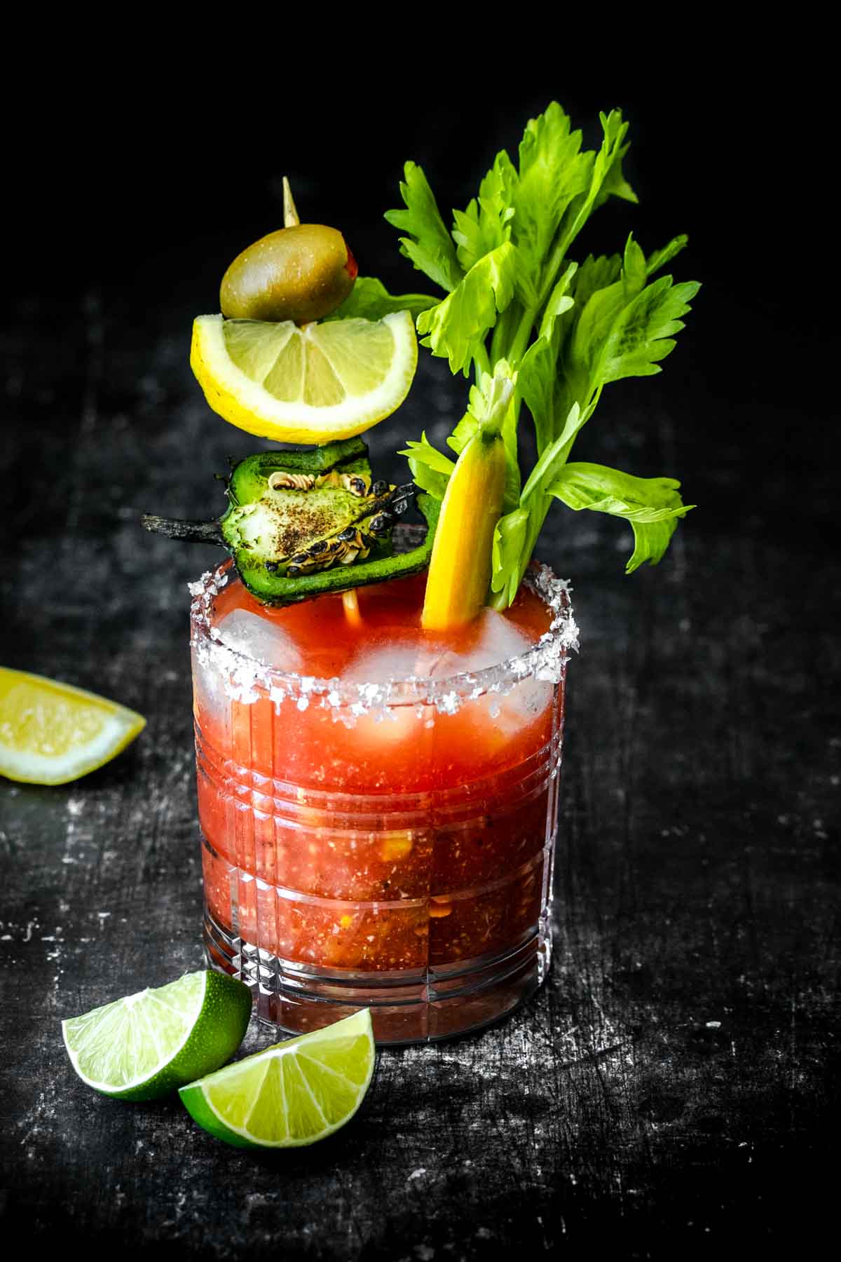 A single cocktail glass with a bloody Mary and ice filled with veggie garnishes.