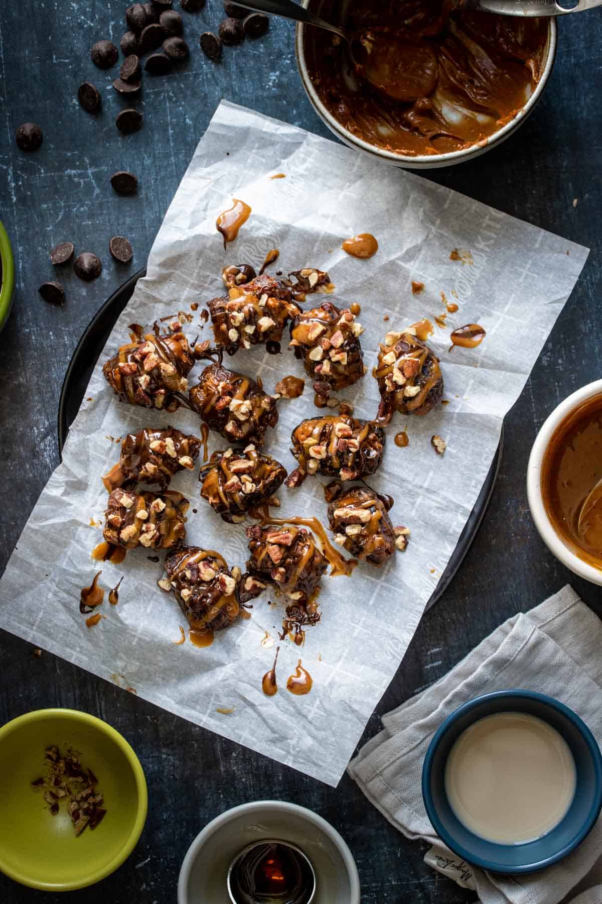 A black plate with a piece of parchment and stuffed dates drizzled with chocolate and caramel