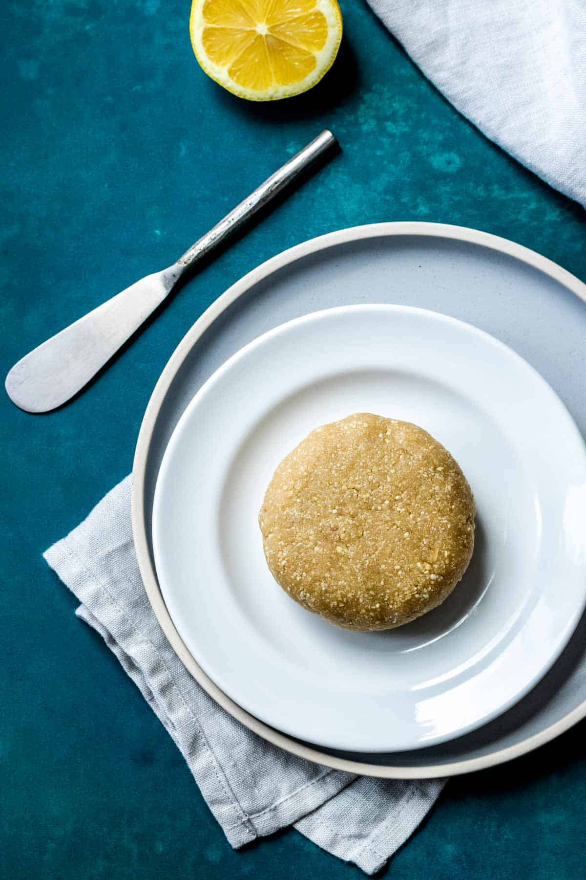 A nut based cheese wheel on a white plate sitting on a grey plate.