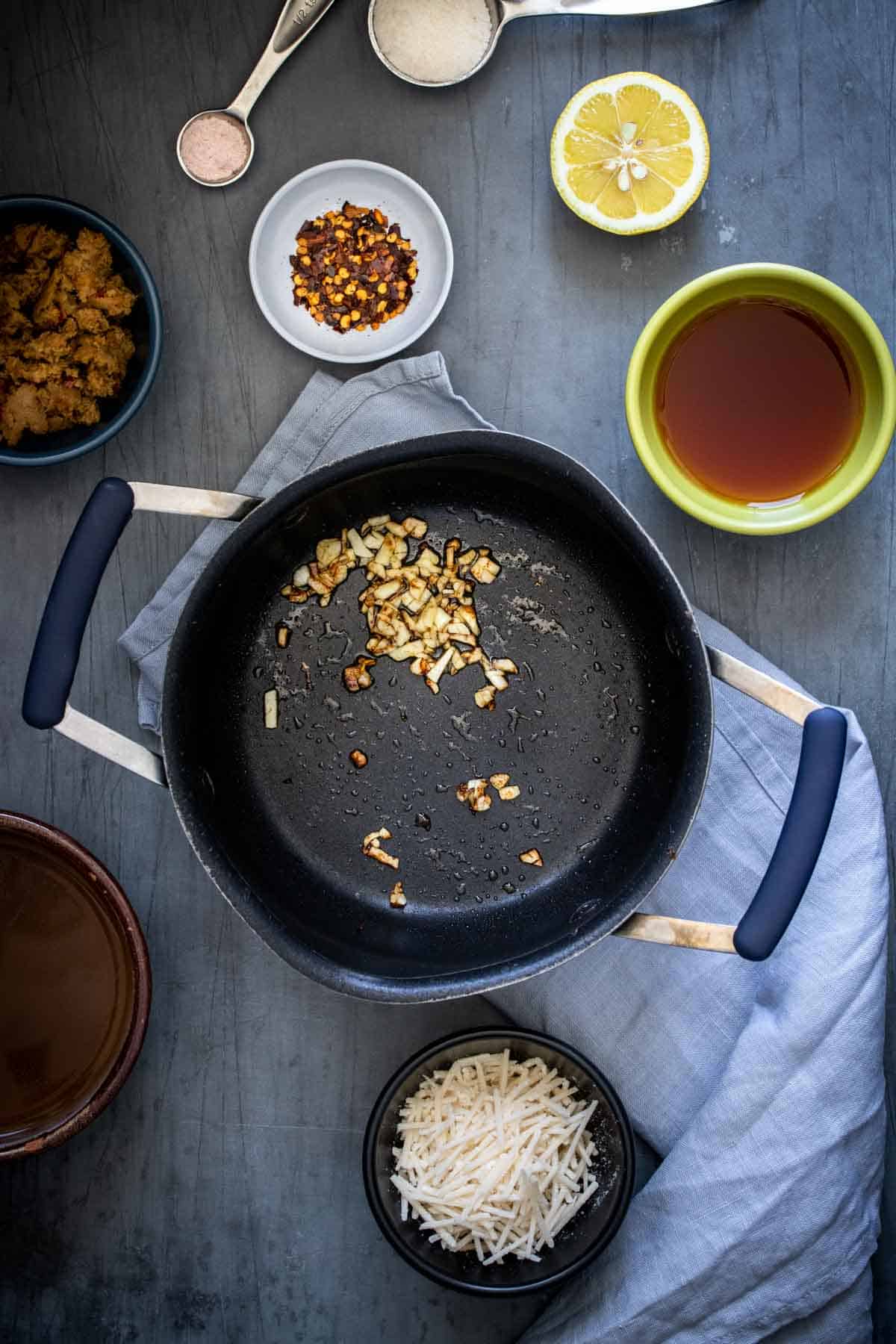 Top view of a black pot with pieces of garlic sauteed and browned in it