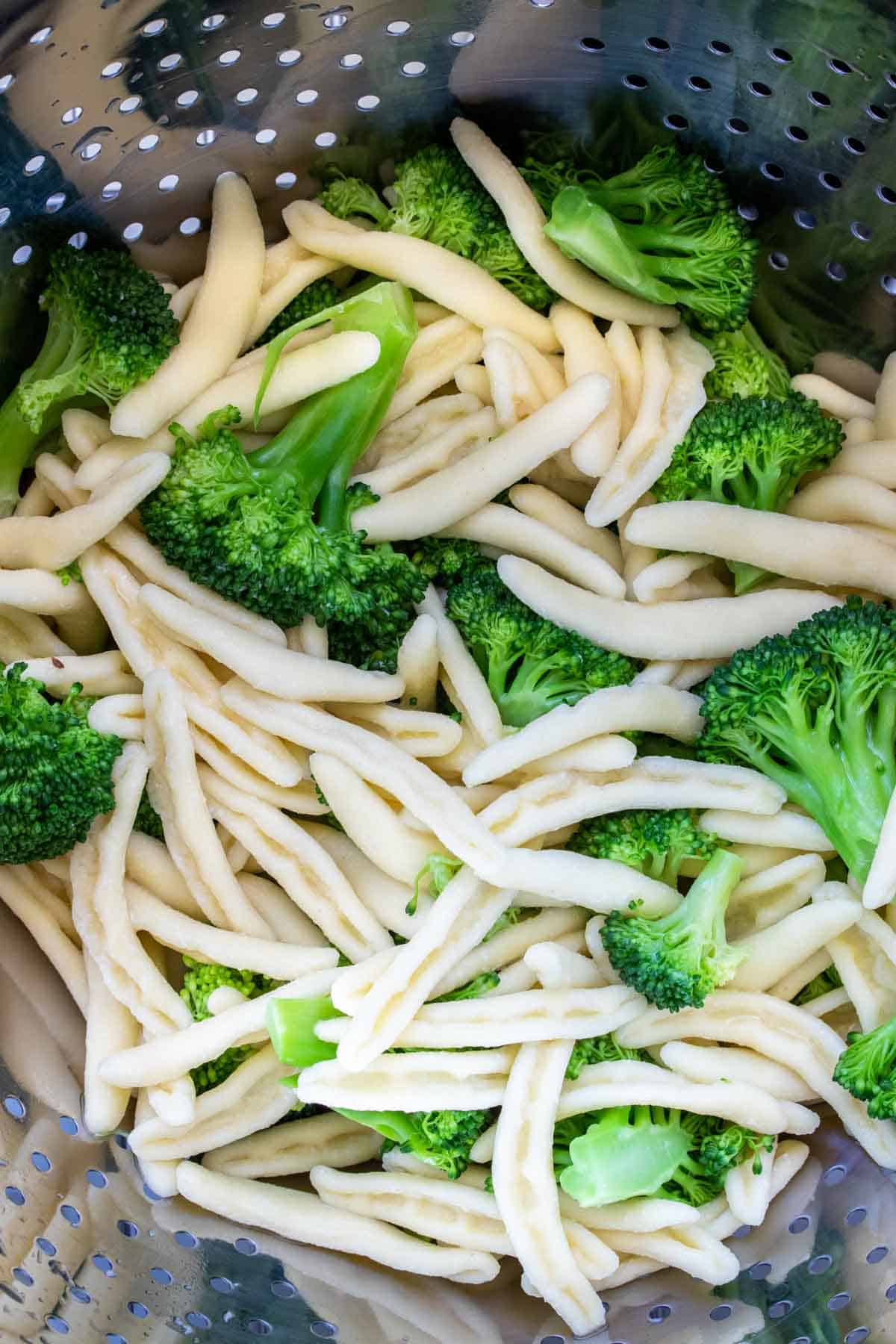 Cavatelli pasta and broccoli in a silver pasta strainer