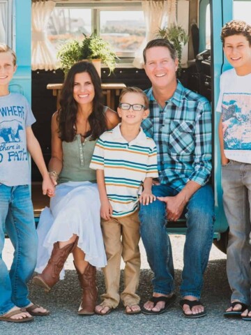 Mom, dad and three young boys smiling at the camera in front of a VW bus