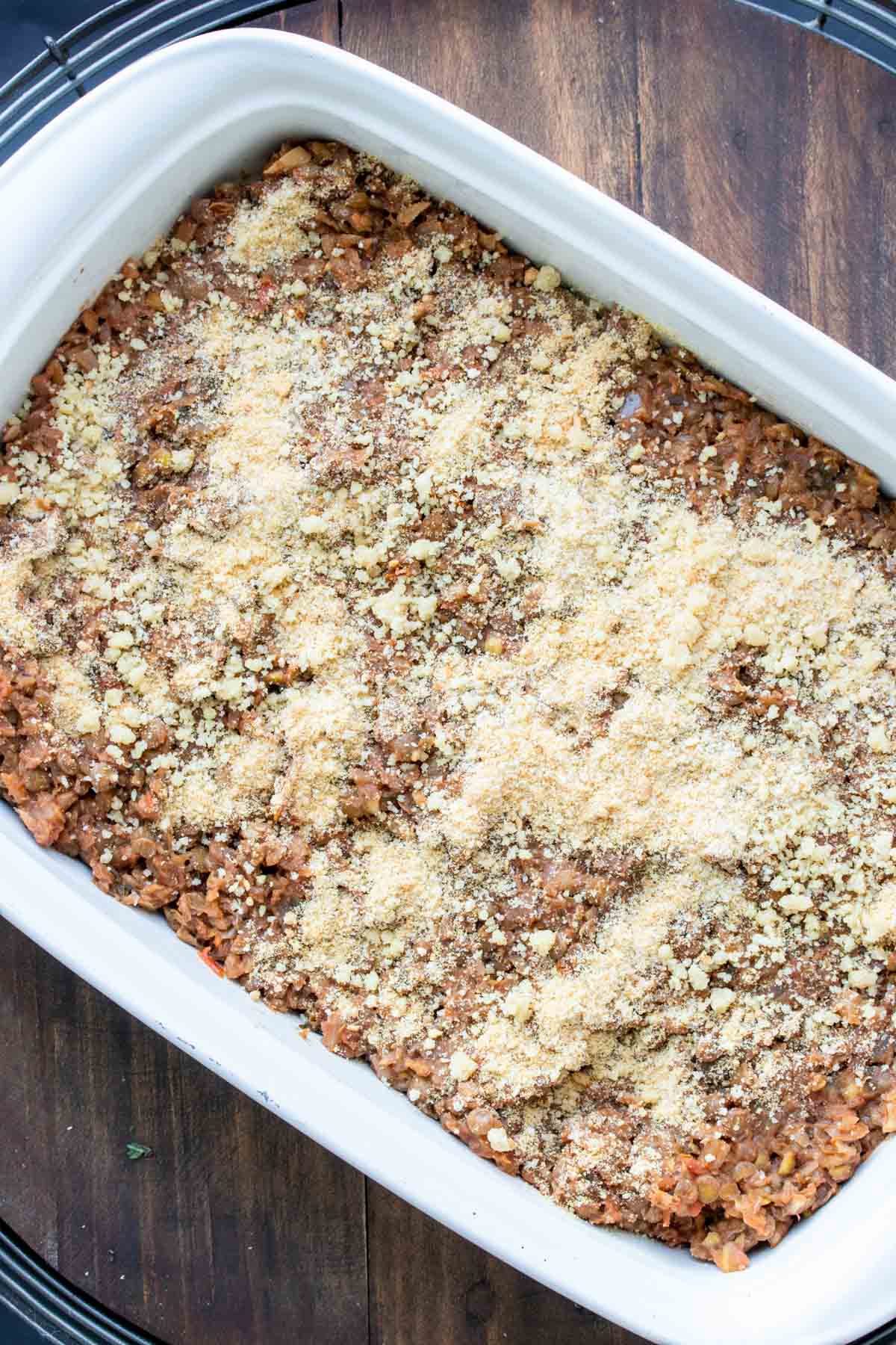 Top view of a white baking dish with a lentil meaty mixture and sprinkled with parmesan.