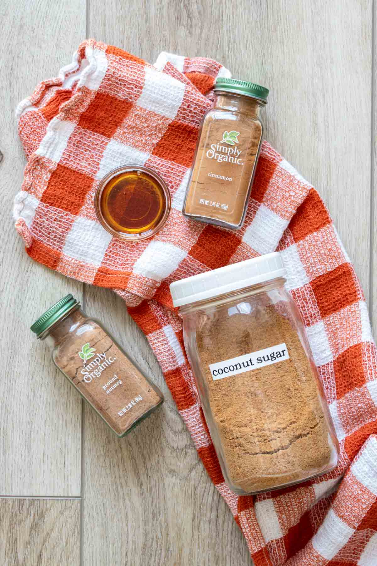 Brown sugar, maple syrup and spices on an orange and white checked towel.