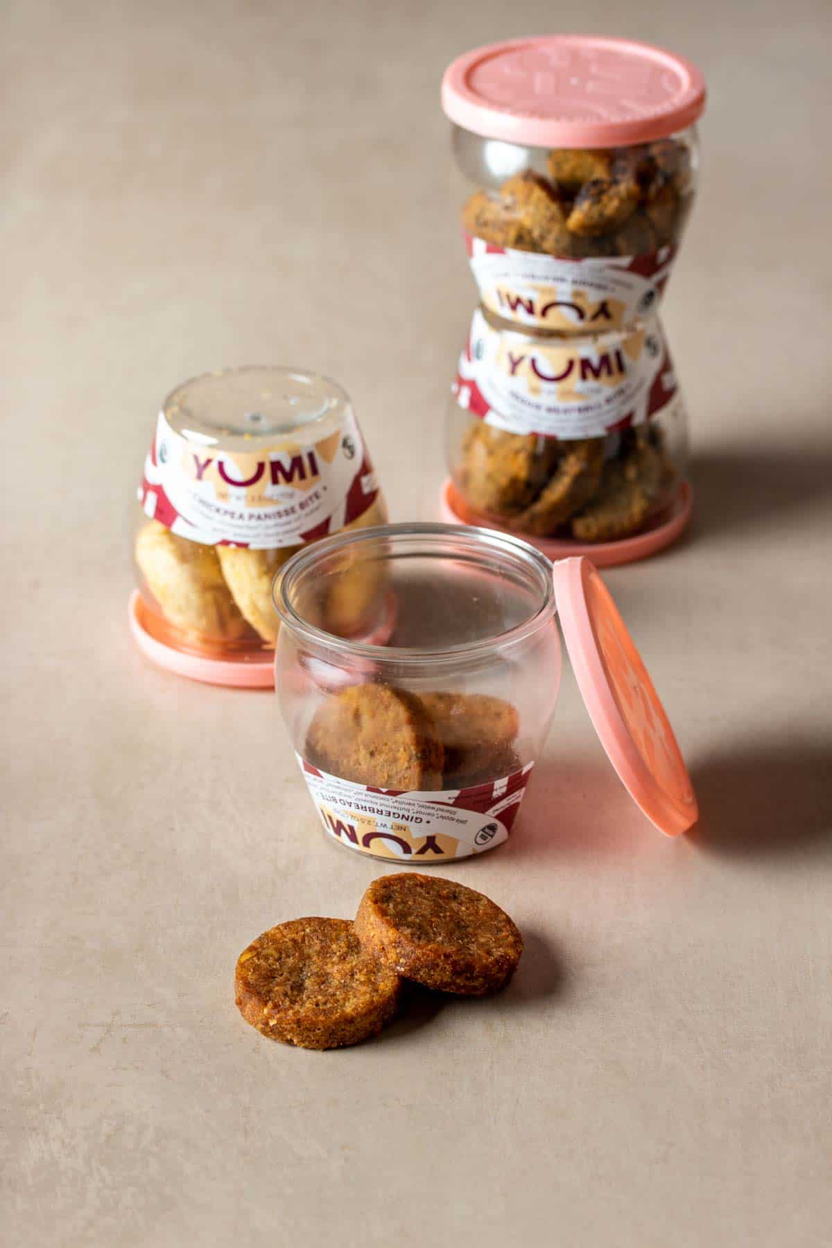 Jars of mini patty baby snacks and pink lids with one open and the lid leaning on it's side.