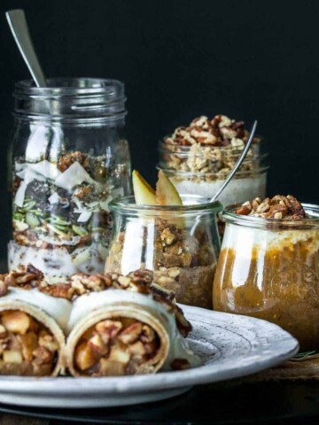 A white plate with apple crepes, jars of pumpkin and pear flavored oats and pudding and a jar with cereal inside.