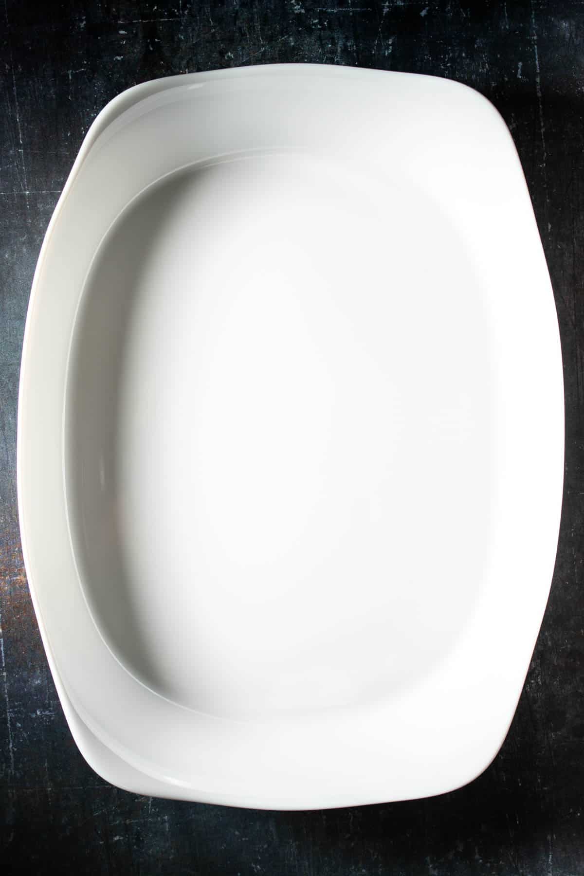 A white rectangular baking dish sitting portrait orientation on a dark surface.