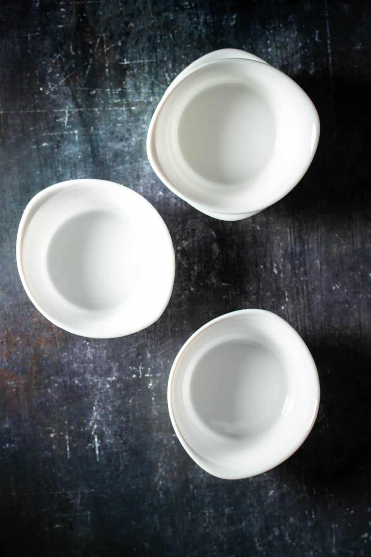 Top view of three small square baking cups on a dark surface.