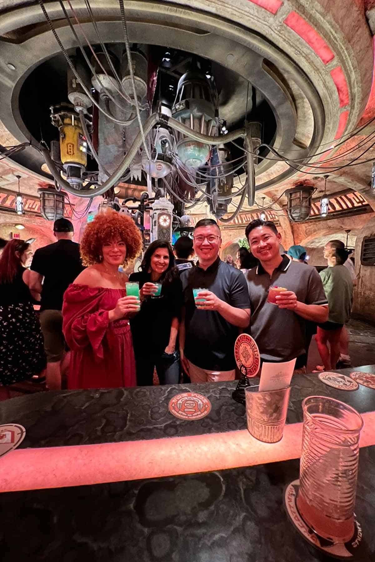 Four people standing next to each other in Oga's Cantina at Disneyland holding cocktails.