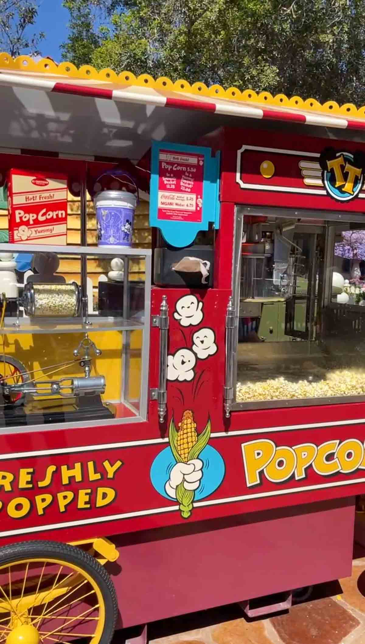 A side view of a red popcorn machine stand at Disneyland.