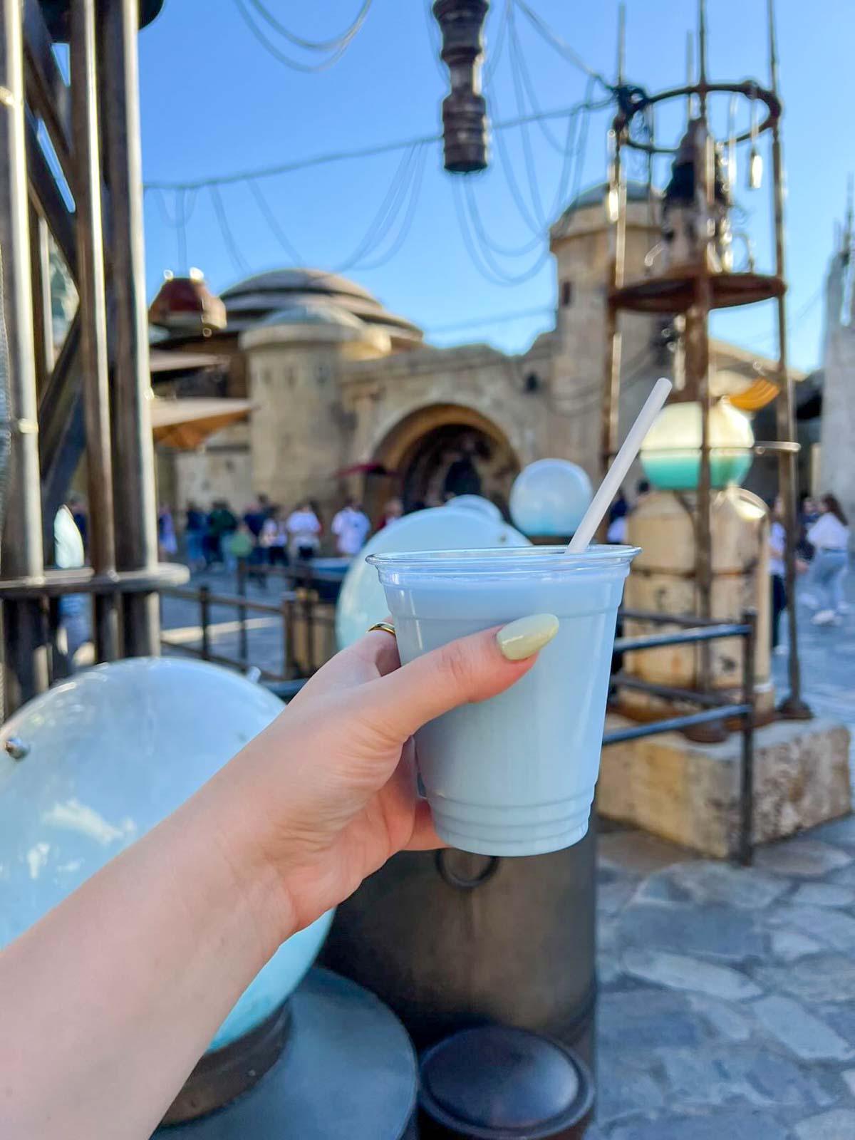 A hand holding a creamy blue drink with a straw in Star wars land at Disneyland.