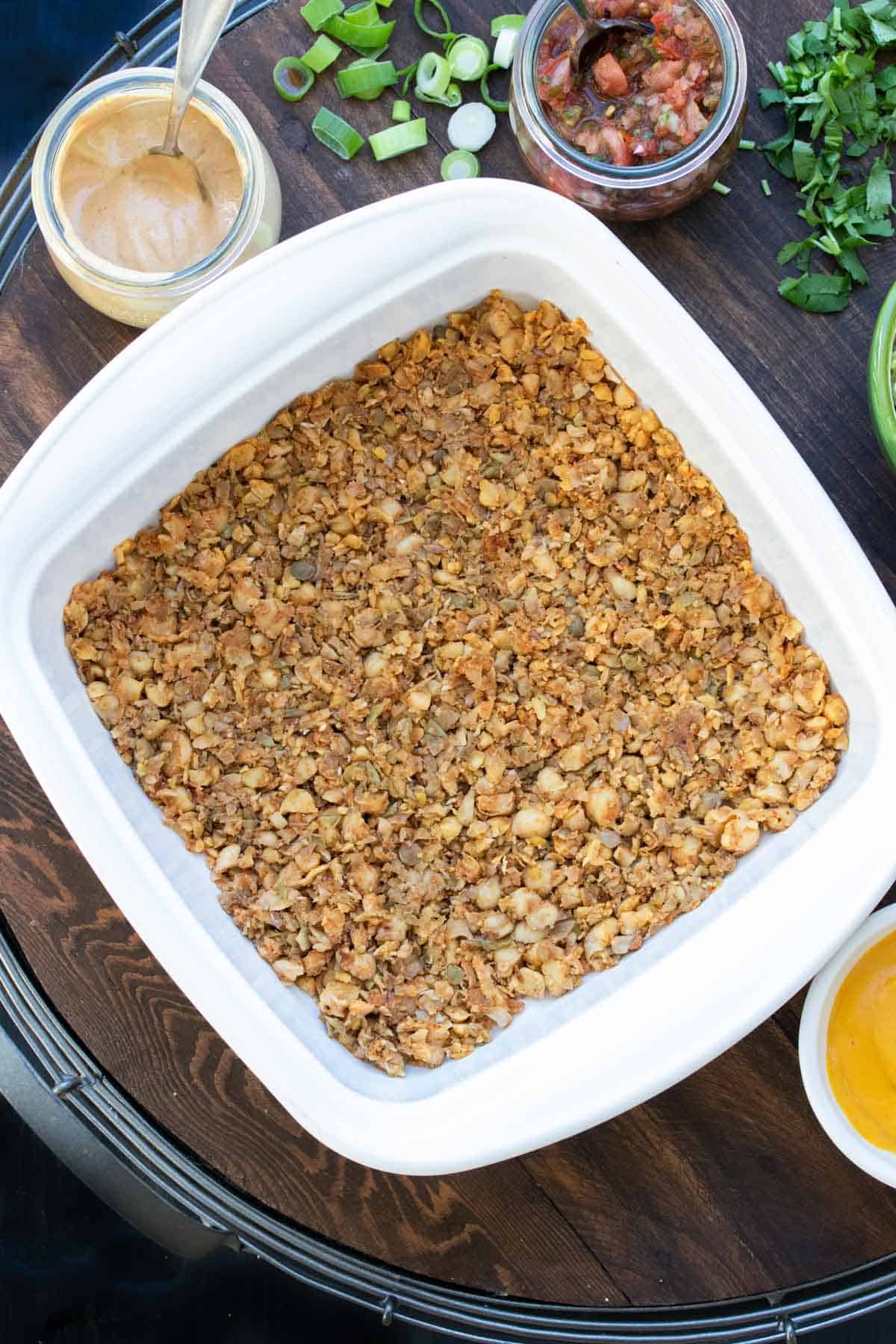 Top view of a white square baking dish with a taco meat in the bottom.