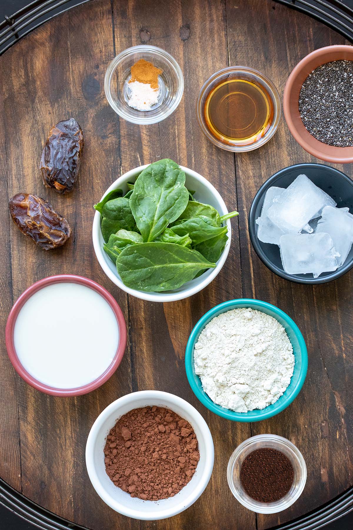 Top view of bowls on a wooden surface with ingredients needed for a coffee smoothie with spinach.