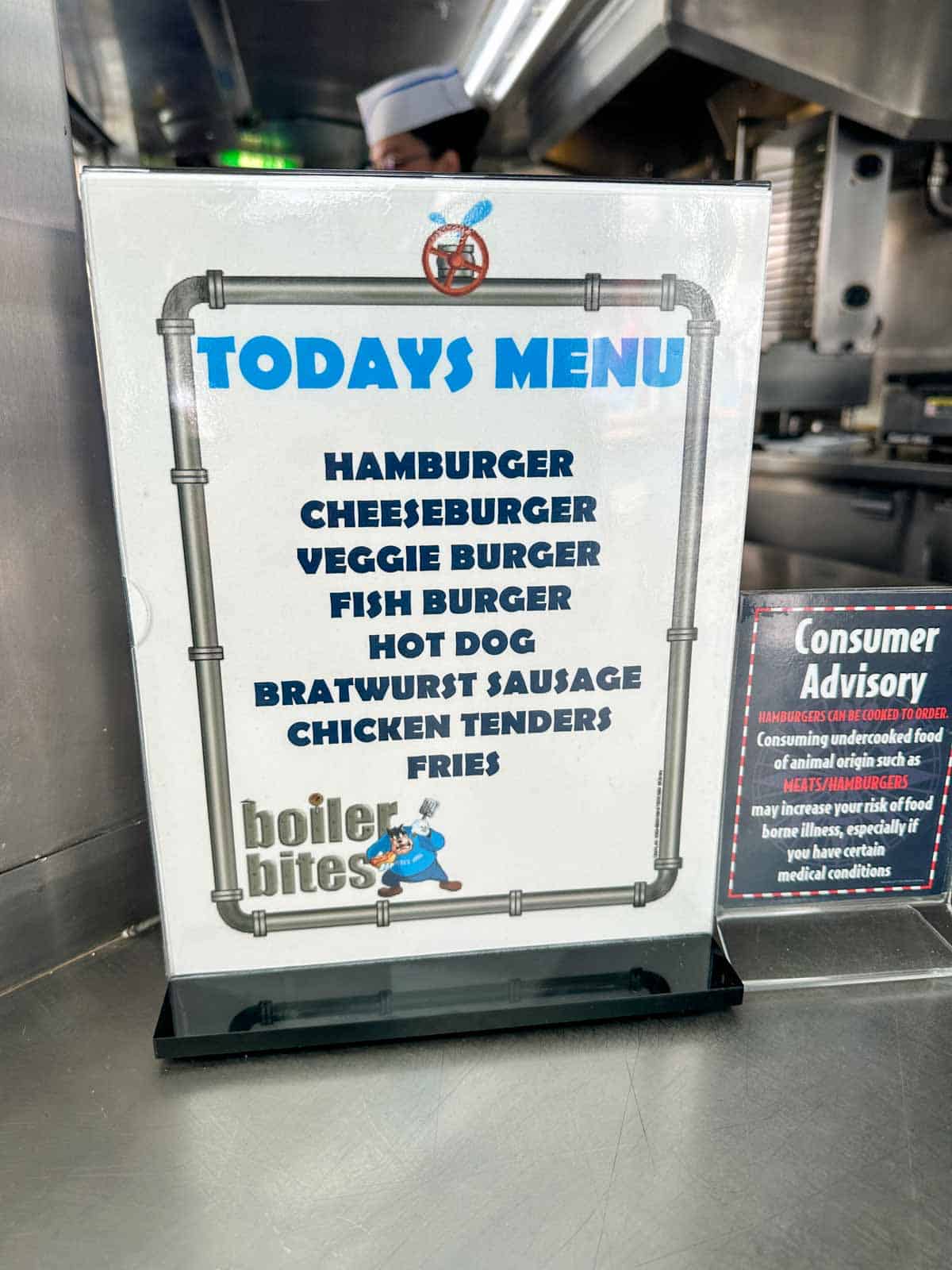 A white sign with blue writing for Today's menu listing grill items like burgers and hot dogs.