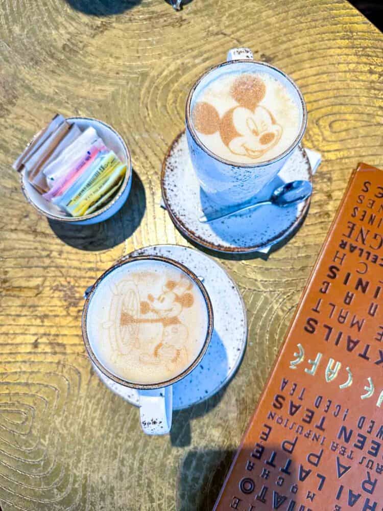 Top view of two mugs of coffee on a table with designs of Mickey's face on them.